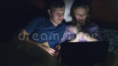 <strong>夫妻</strong>，男人和女人，在<strong>睡觉</strong>前在卧室的床上用笔记本电脑看电影。 看恐怖电影，观众